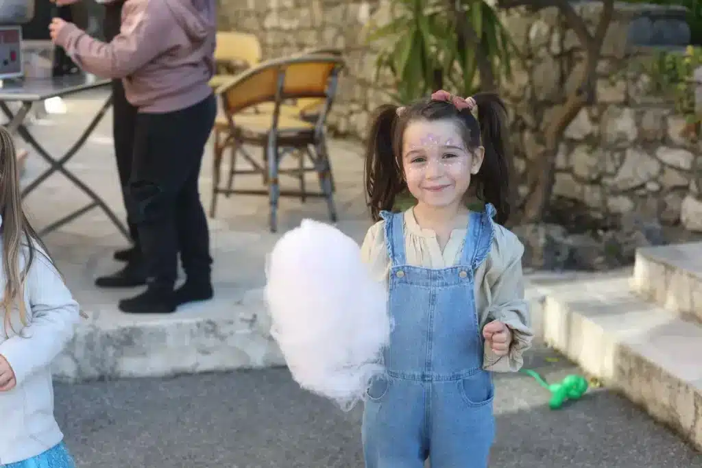 Une enfant souriante avec son maquillage et une grande barbe à papa
