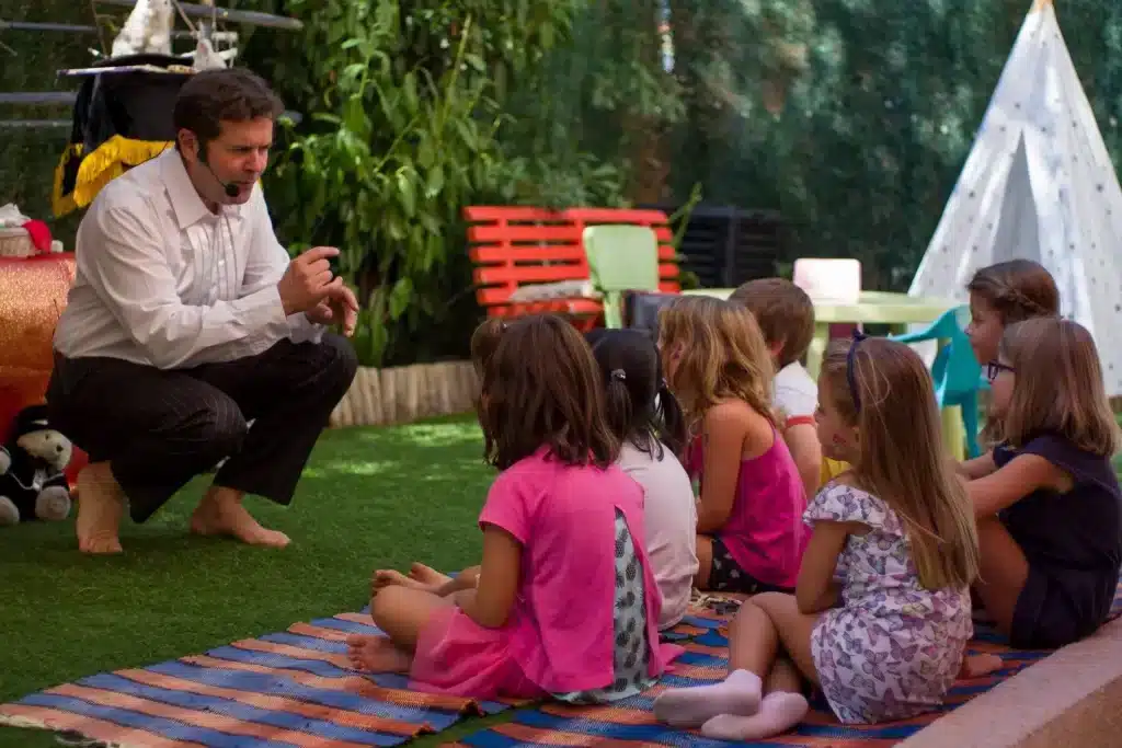 Des enfants attentifs au spectacle de Danny dans un jardin
